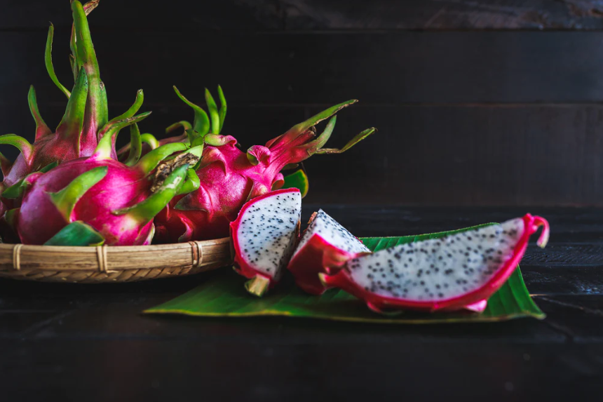 A fruit basket filled with dragon fruit next to a sliced dragon fruit