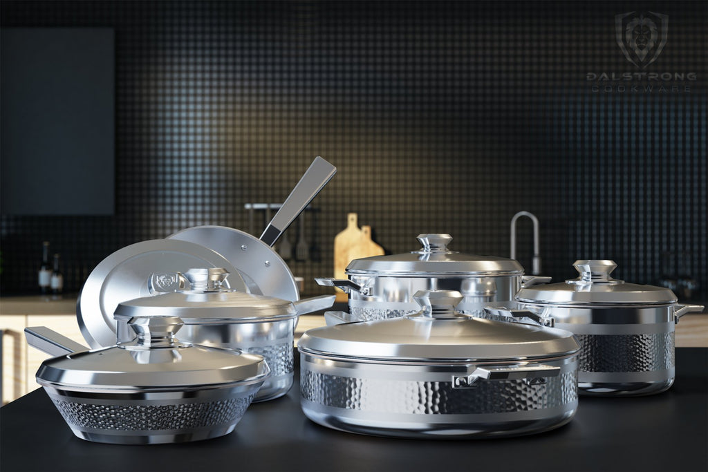 12 piece of silver cookware on a kitchen countertop with black tiled walls in the background