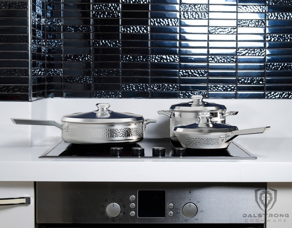 Three pieces of silver cookware with lids on a kitchen stove top