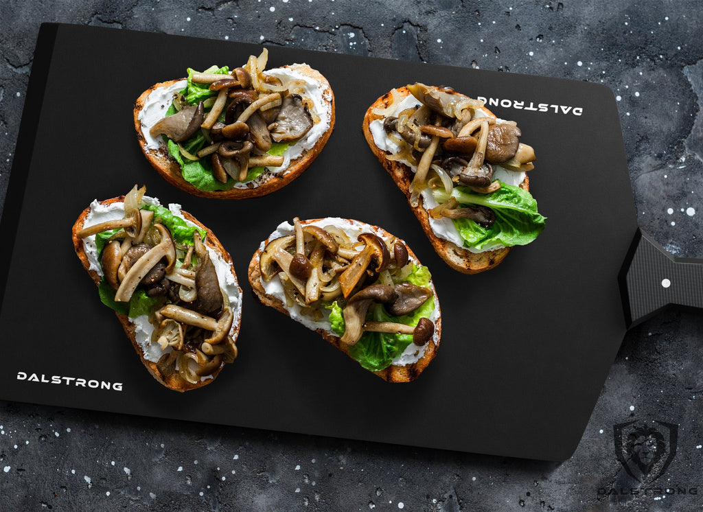 Four slices of toasted bread with cooked mushrooms on top of a black cutting board
