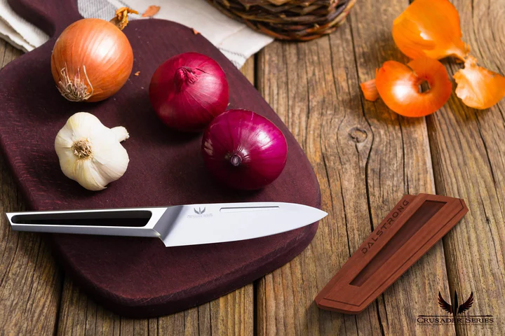 A garlic bulb and thee onions beside the Paring Knife 3.5" Crusader Series | NSF Certified | proformapeakmarketing on top of a chopping board on a wooden table