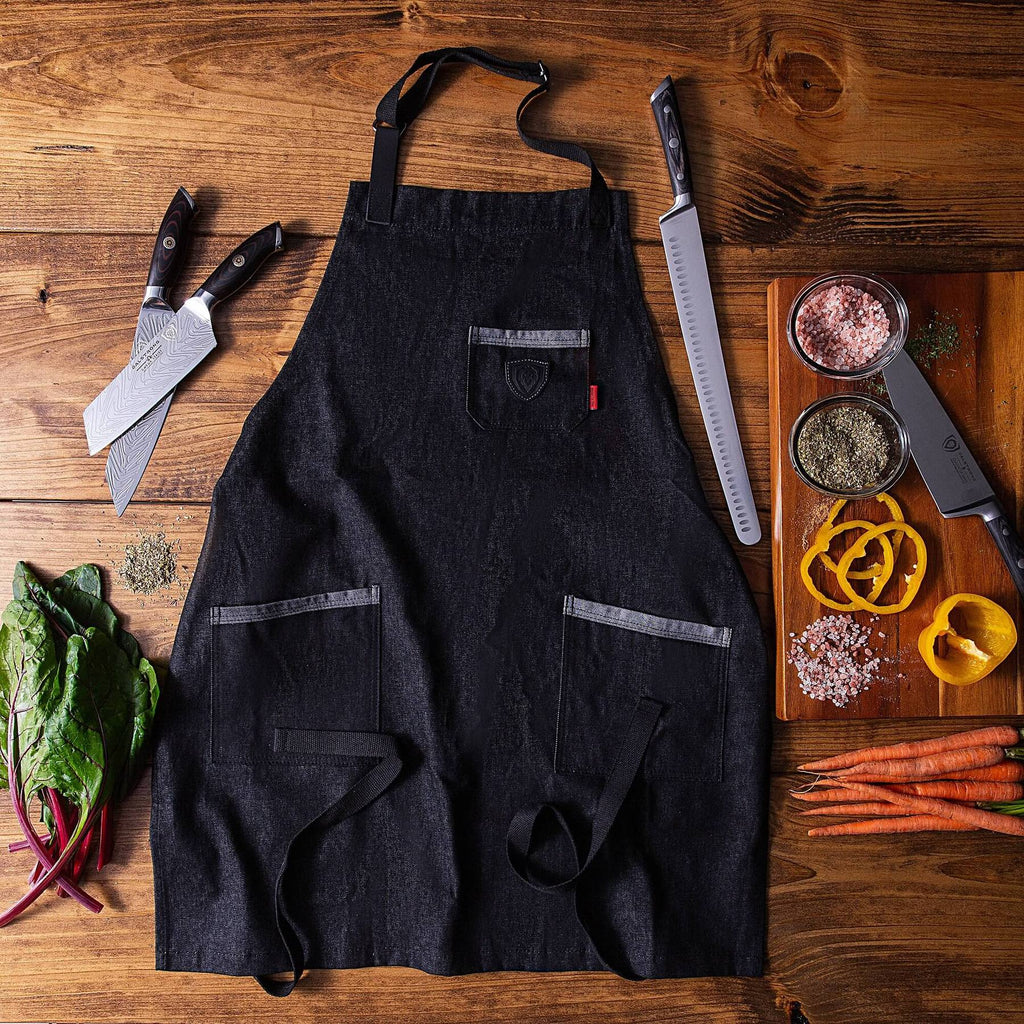 Black apron on a wooden floor next to chopped vegetables and sharp kitchen knives