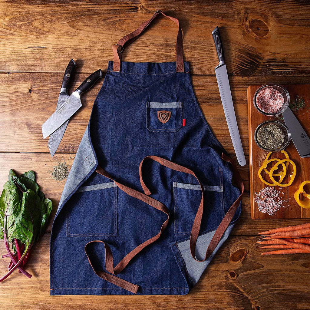 Navy blue kitchen apron with brown straps next to kitchen knives and sliced vegetables