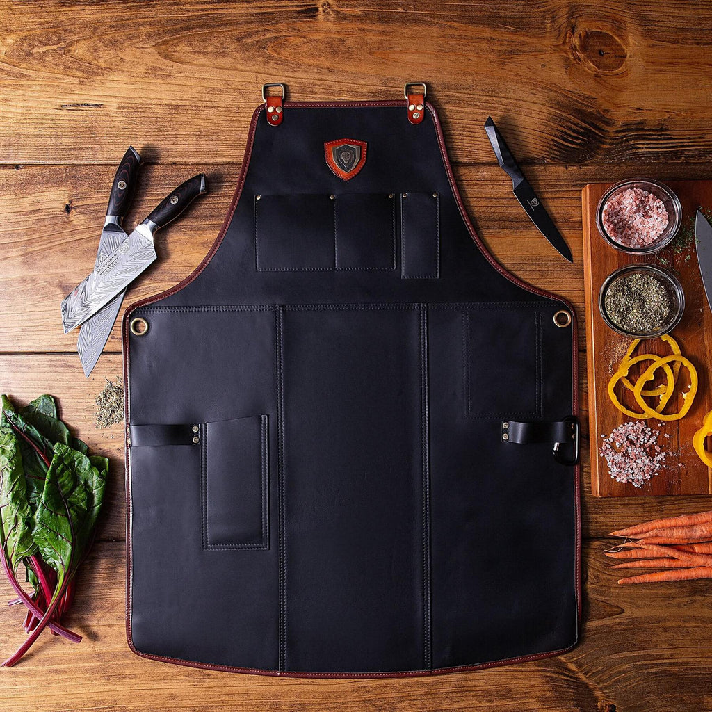 Black leather kitchen apron on a wooden floor next kitchen knives and chopped vegetables