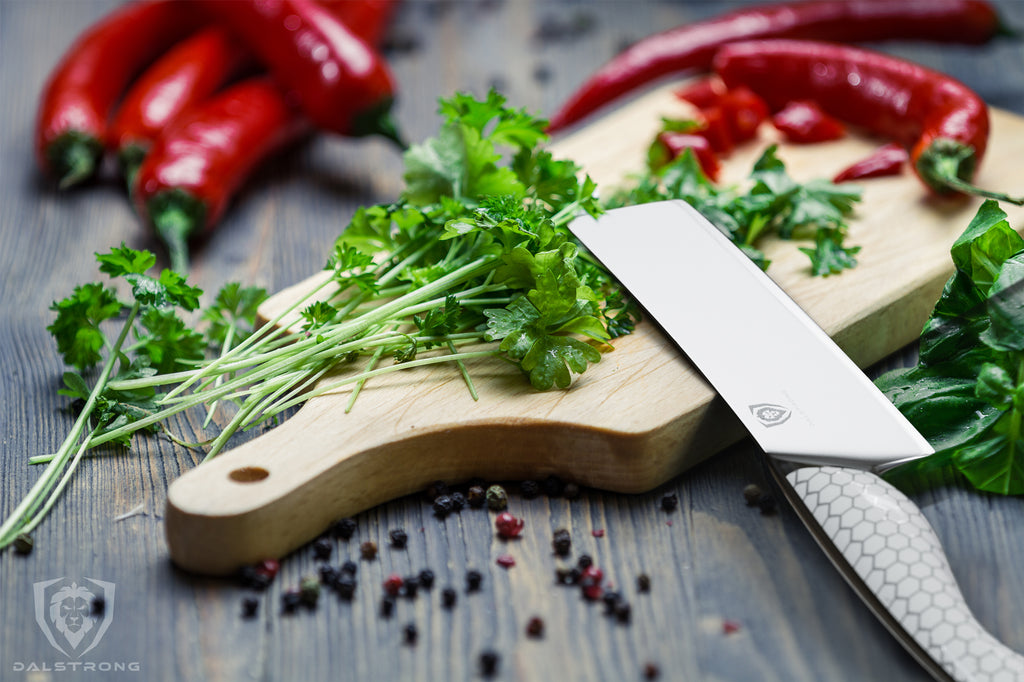 Nakiri knife laying out cutting board with chopped herbs