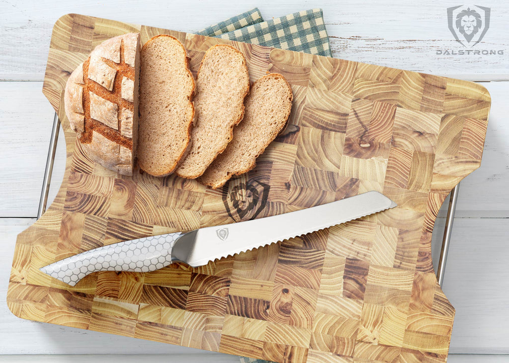 A serrated knife with a snake skin pattern handle on a large cutting board next to sliced bread