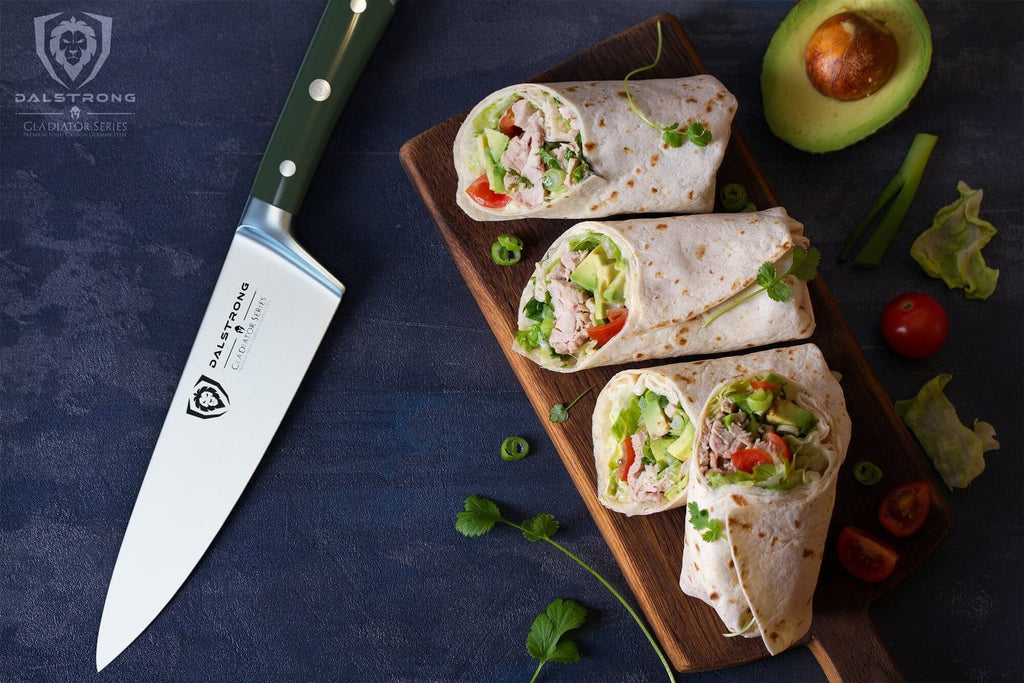Sharp chef knife with green handle next to a cutting board full of sandwich wraps