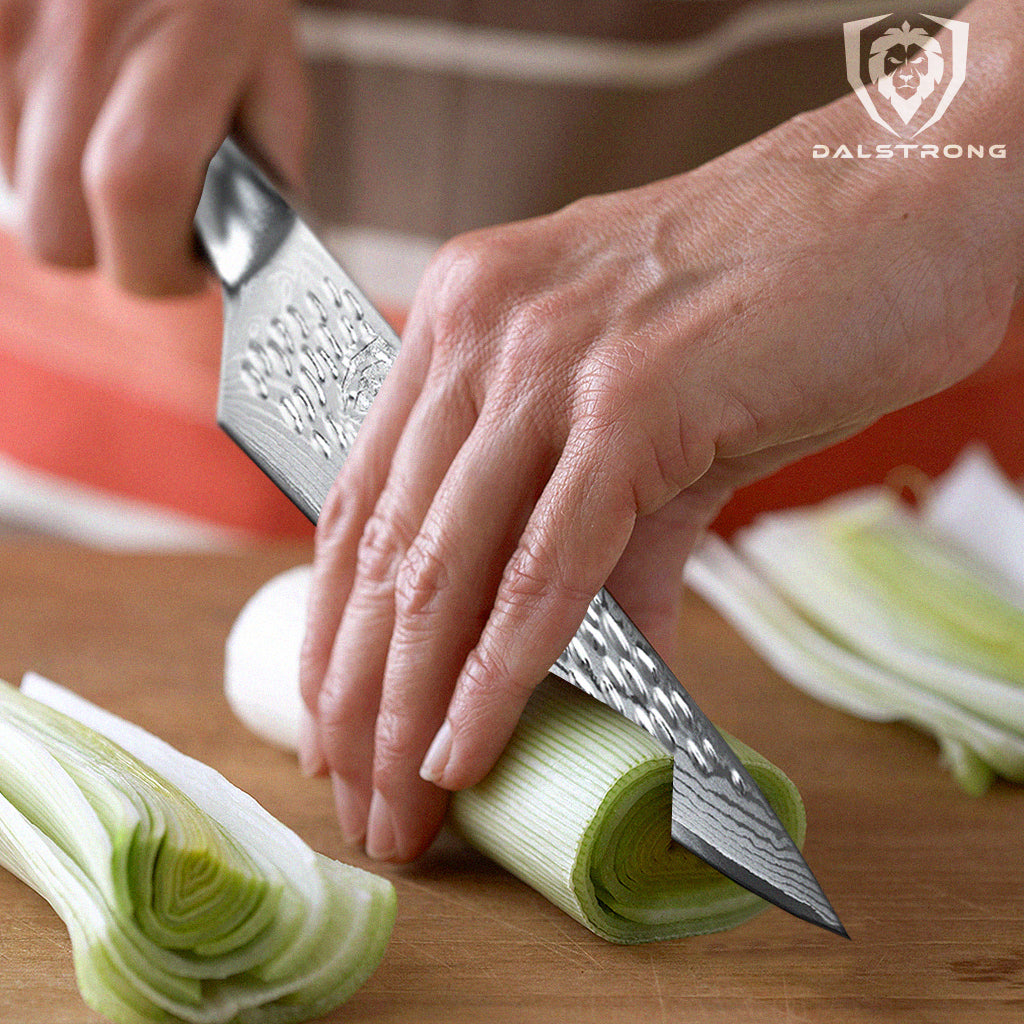 chef knife slicing a leek on a kitchen table