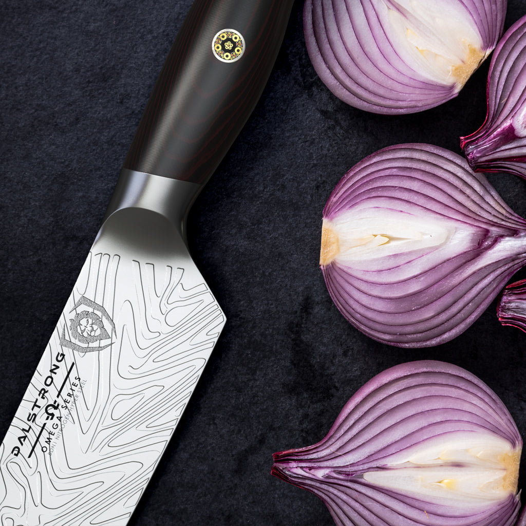 Close up of red onions chopped in half against a black background next to a stylish kitchen knife