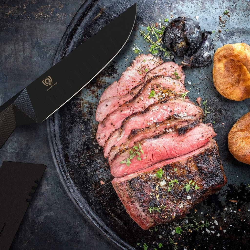 A sharp black steak knife next to a plate of medium rare steak