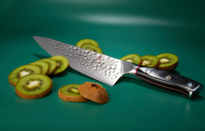 Twelve slices of fresh kiwi beside the Chef's Knife 8" Shogun Series ELITE proformapeakmarketing in a green surface
