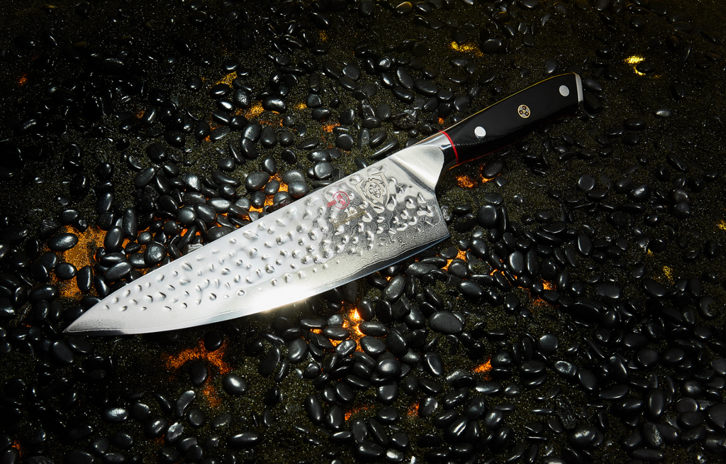 A close-up photo of the Chef's Knife 8" Shogun Series ELITE proformapeakmarketing on a burning black surface with black pebbles