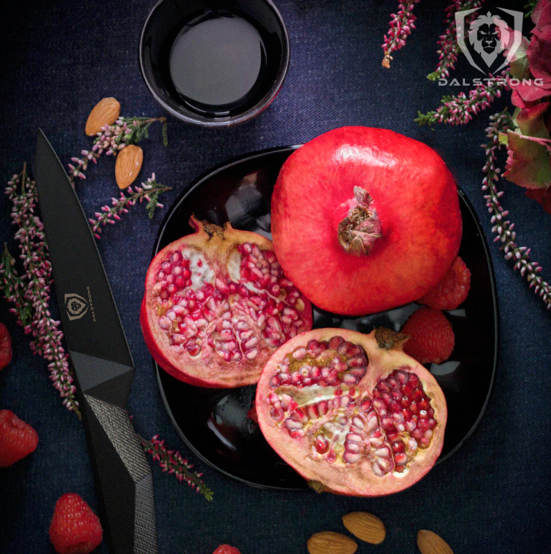 A pomegranate sliced in half next to a small black kitchen knife