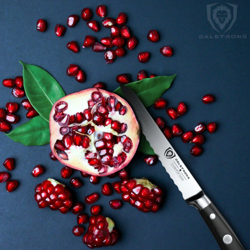 A pomegranate half surrounded by red seeds on a dark blue surface