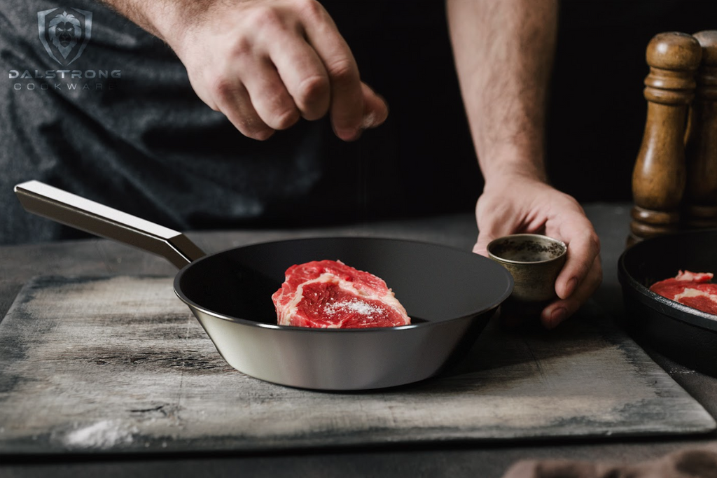 A photo of a mans hand seasoning the steak inside the 10" Frying Pan & Skillet ETERNA Non-Stick Oberon Series proformapeakmarketing