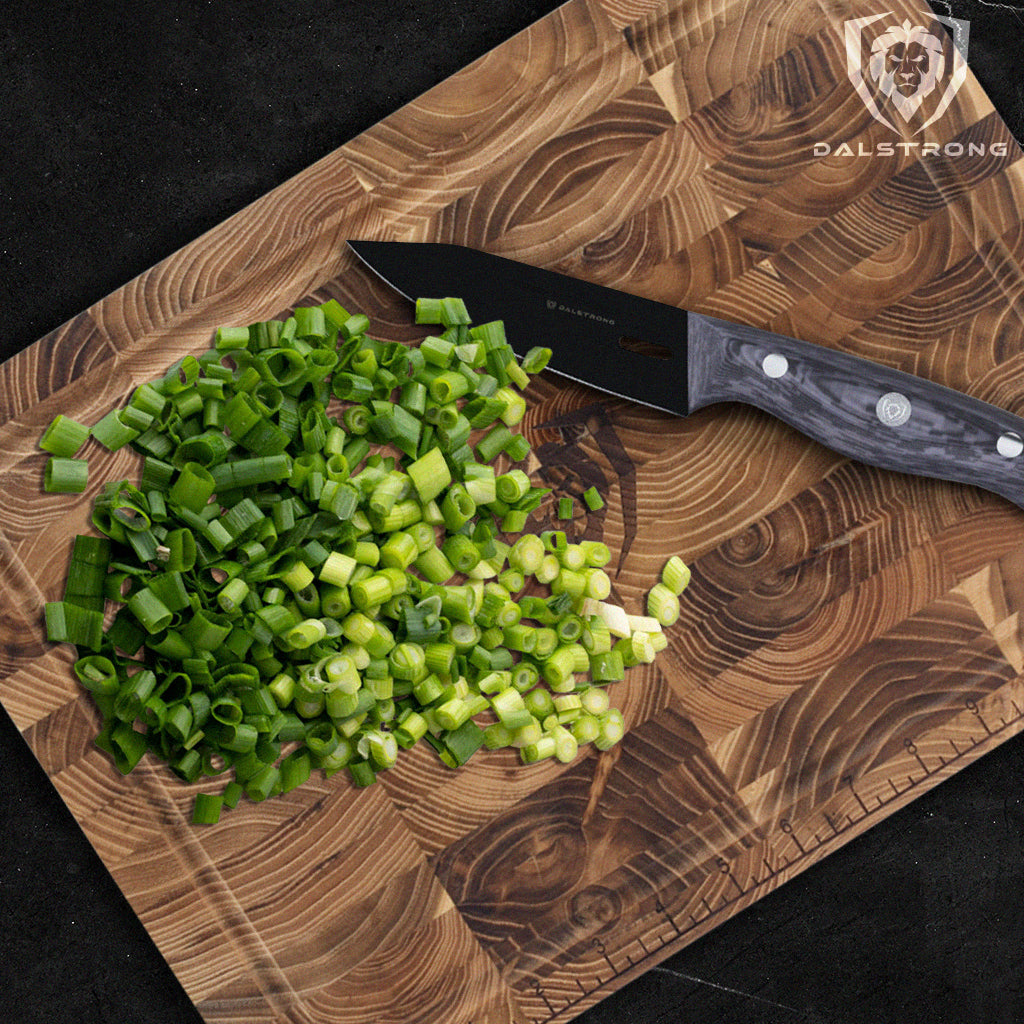 Diced green onion on a wooden cutting board next to a black paring knife