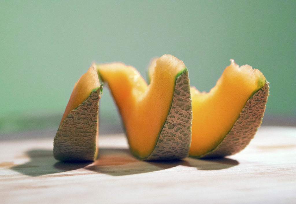 Ripe cantaloupe sliced in three on a wooden surface.