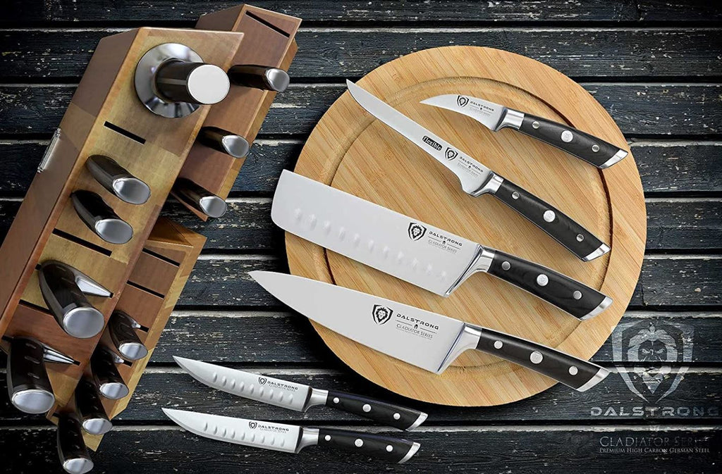 proformapeakmarketing Gladiator Series 18-piece Colossal Knife Block Set on a black wooden table with a few of its knives laid outside of the block on a wooden circular tray.
