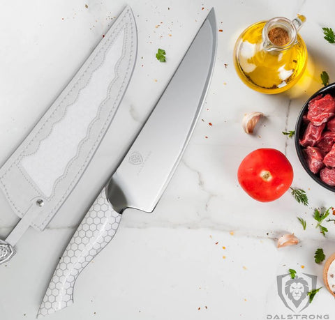 proformapeakmarketing Frost Fire Series Chef knife on a marble counter top next to its white leather sheath.