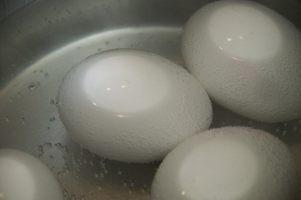 Some eggs boiling on a pot over low heat.