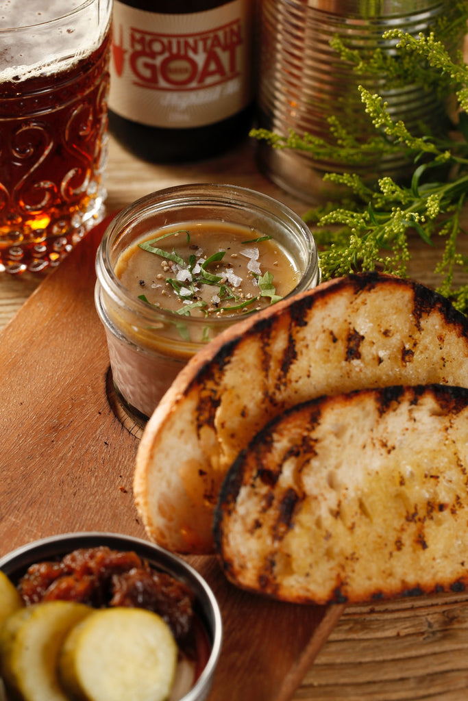 Brown gravy on a wooden table with toasted bread on the side.
