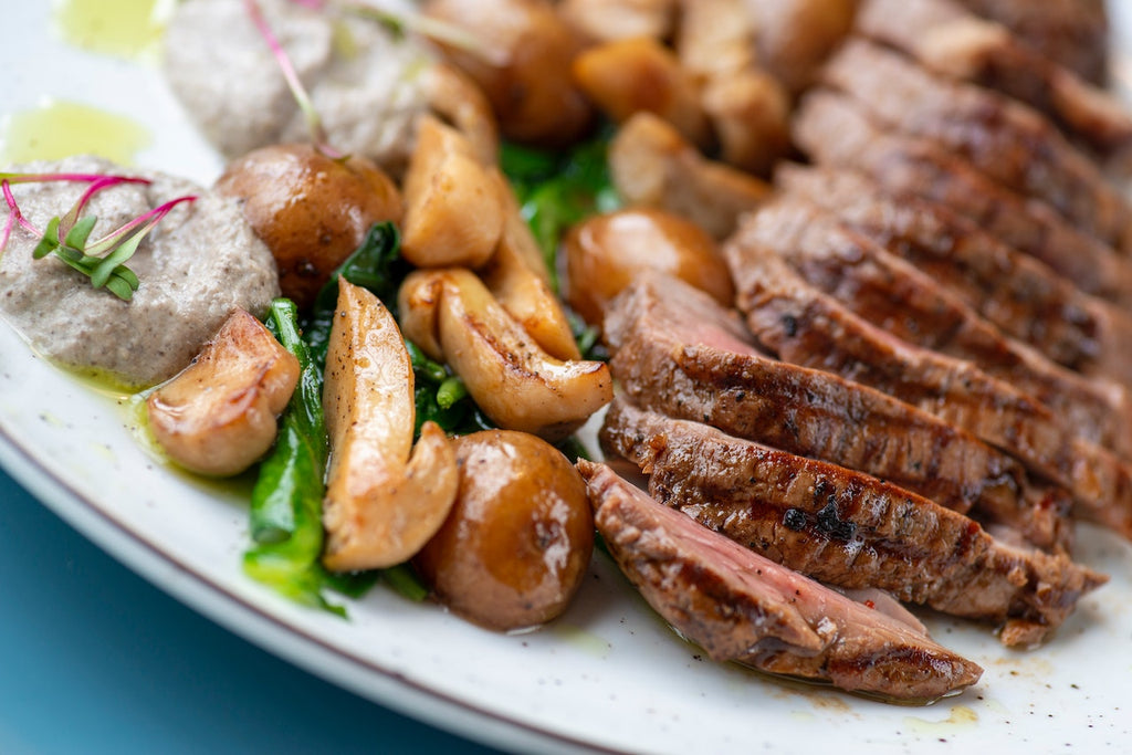 Close-up shot of a freshly cooked flank steak dish on a white plate.