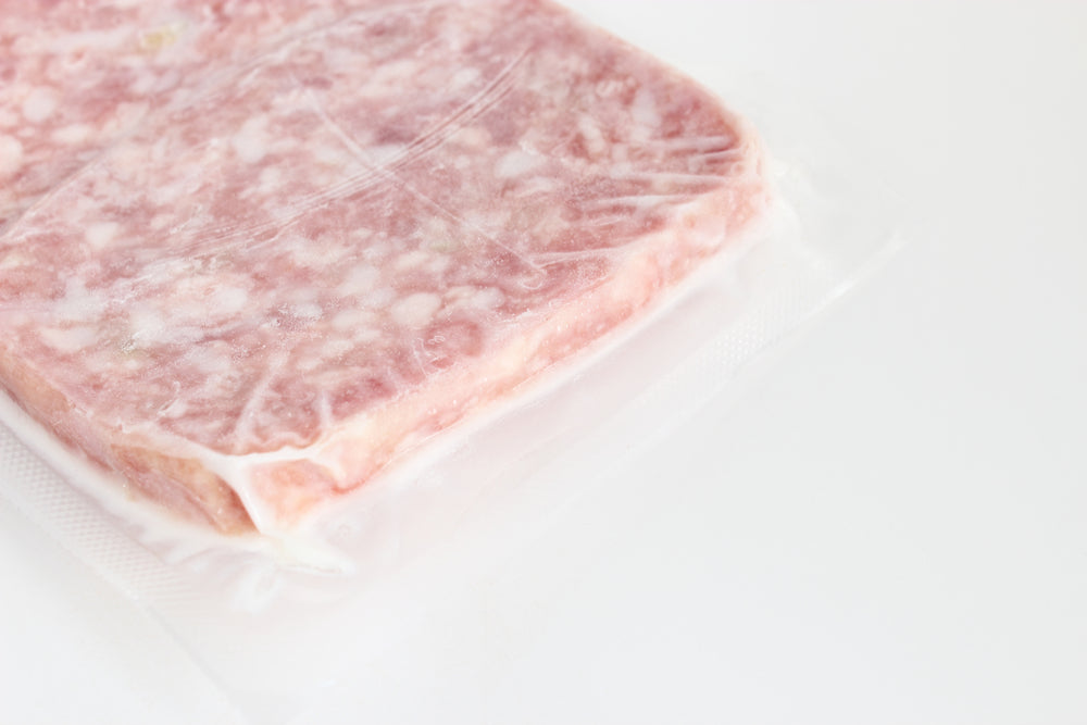Vacum sealed frozen meatloaf against a white background