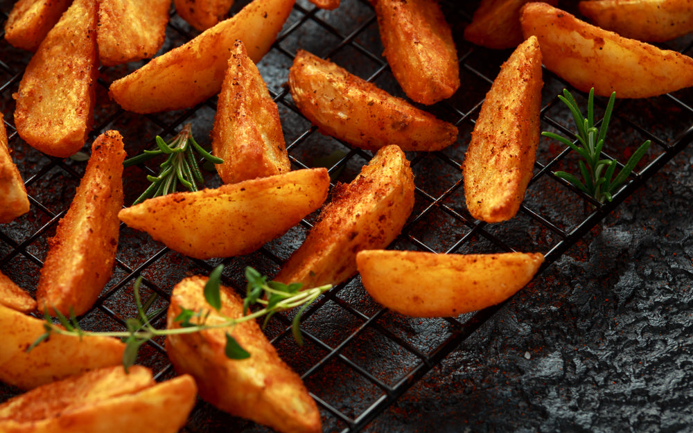 Golden brown cooked potato wedges on a baking sheet with green garnish