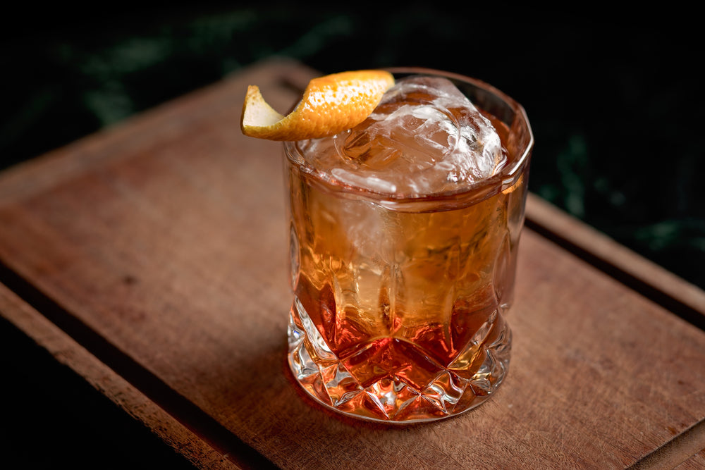 Old fashioned, classic cocktail served on the rocks on a wooden cutting board