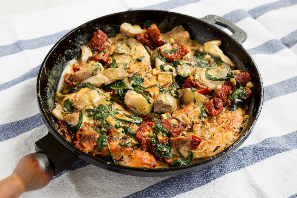 creamy tuscan chicken in pan on tablecloth