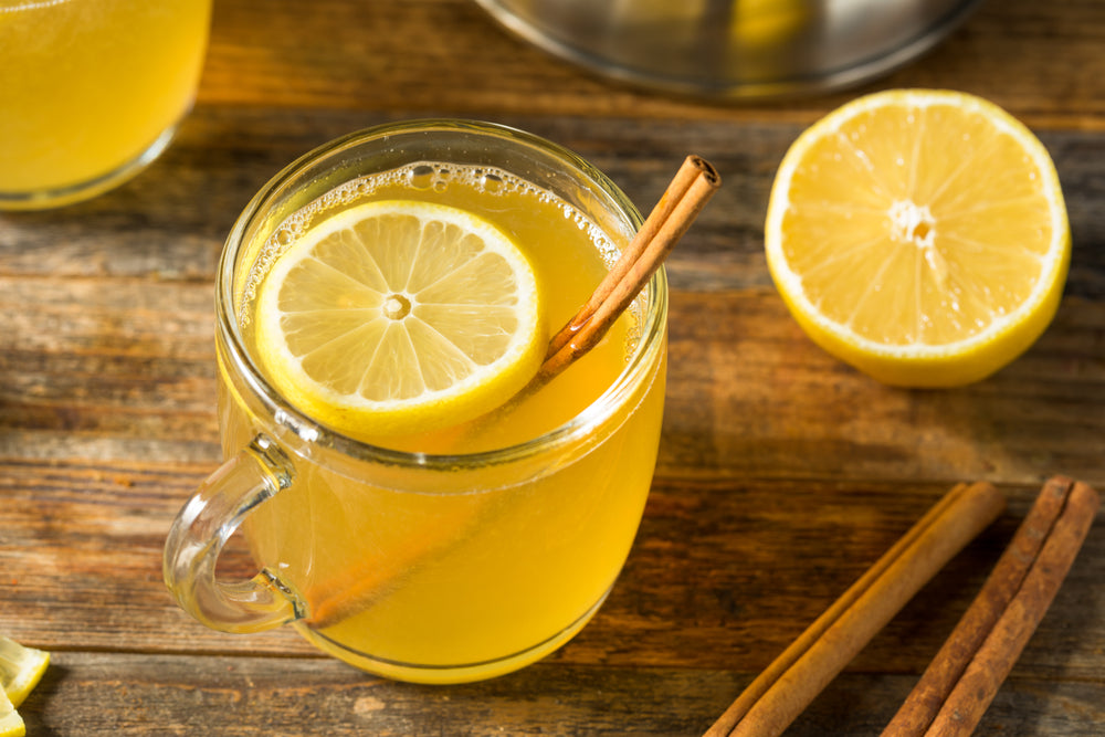 Homemade Hot Toddy Cocktail with Whiskey and Lemon on a wooden surface