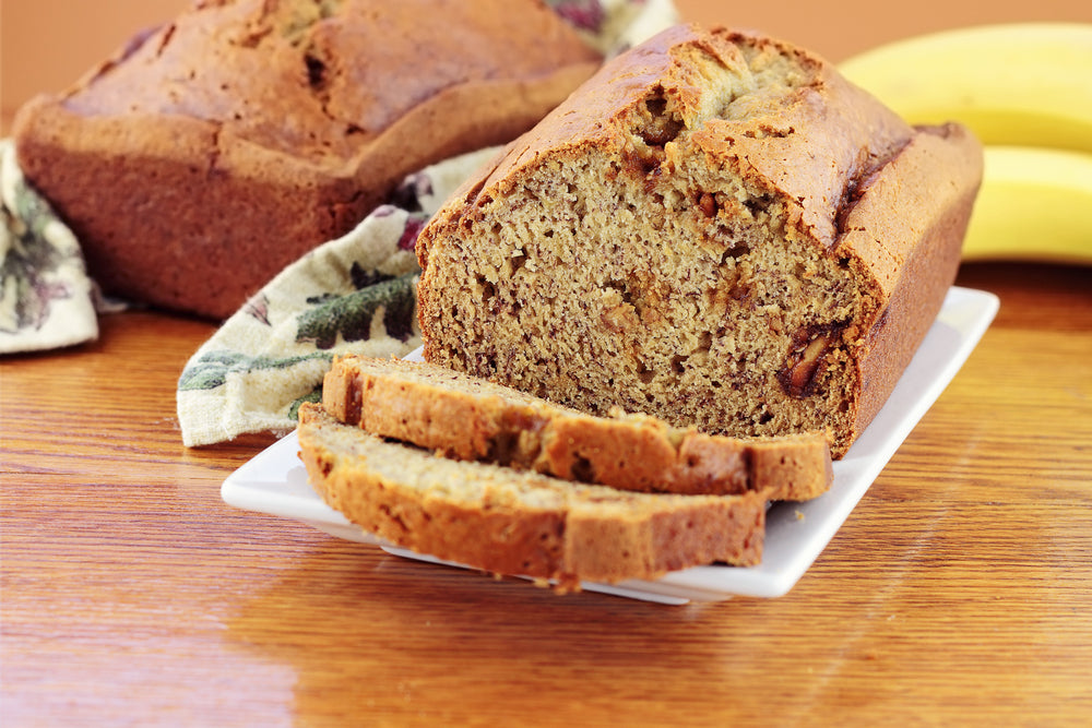 Banana bread loaf on a white plate with two slices cut from the front