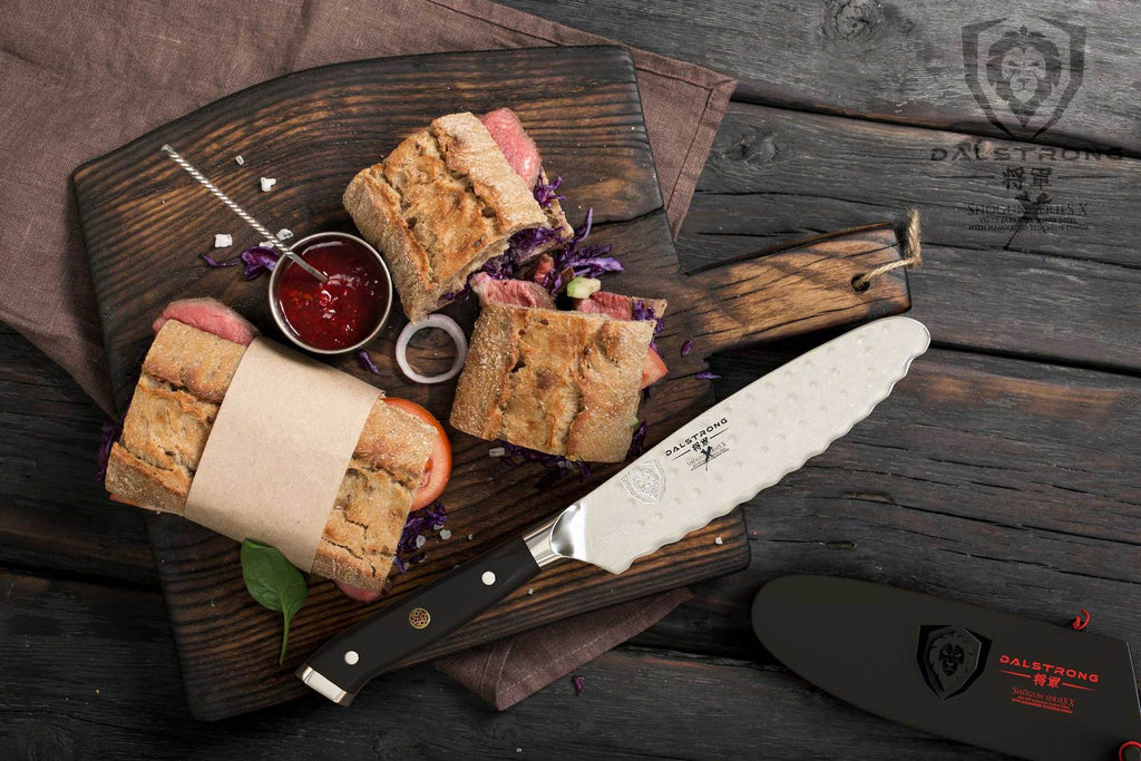 Two sandwiches on a cutting board next to a utility knife