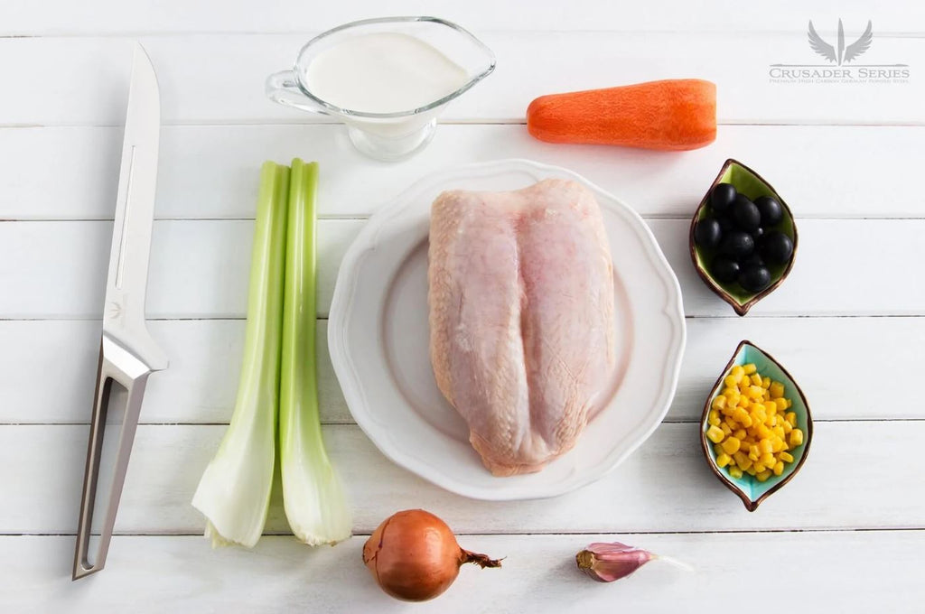 proformapeakmarketing Crusader Boning Knife on a white wooden table surrounded by chicken breast and other ingredients.