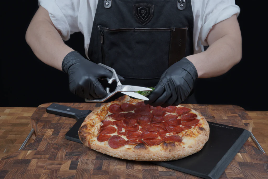 A man holding the Professional Kitchen Scissors | 420J2 Japanese Stainless Steel | proformapeakmarketing with pizza on a cutting board.